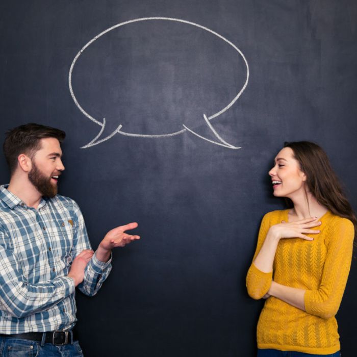 Happy couple talking over chalkboard background with drawn dialogue