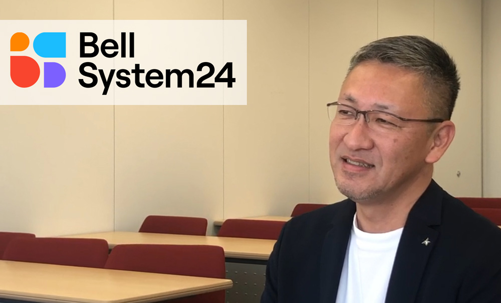 ベルシステム24のロゴと背景に早川氏がインタビューに答えている写真