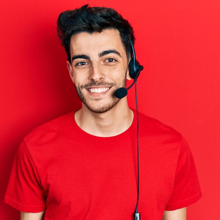 Young hispanic man wearing call center agent headset looking positive and happy standing and smiling with a confident smile showing teeth