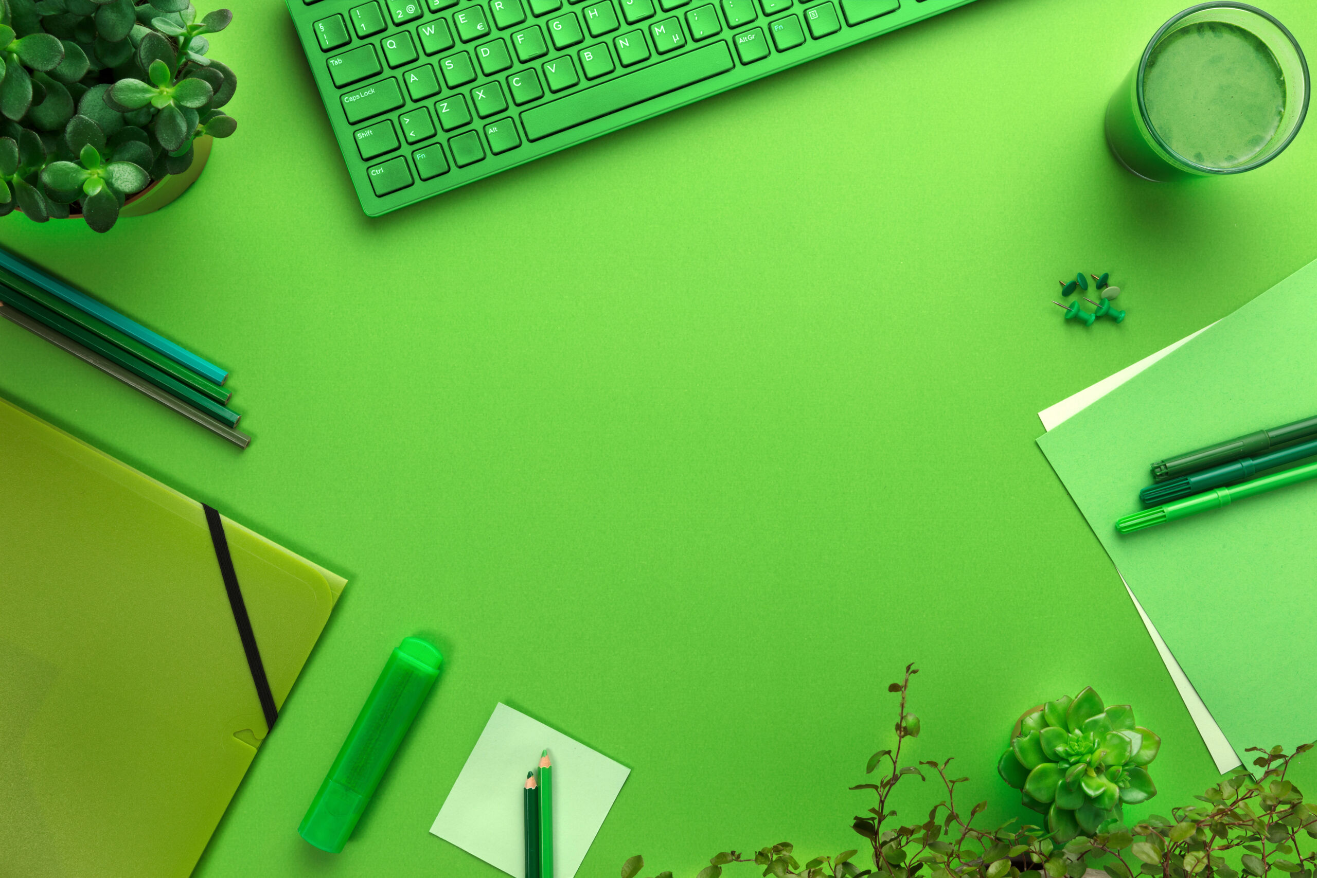 High angle view of a environmental concept of a green office desk with computer, supplies, green algae drink and plants. Living green and save the planet. Top view with copy space.